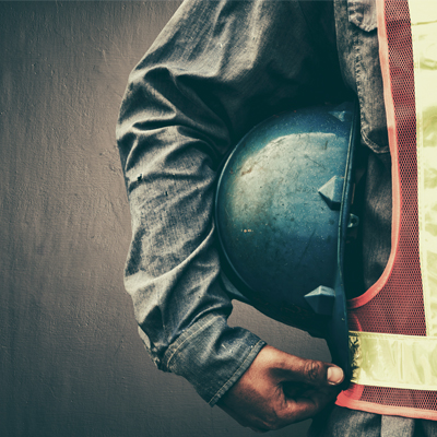builder in a hi-vis jacket holding a builders hat by their side